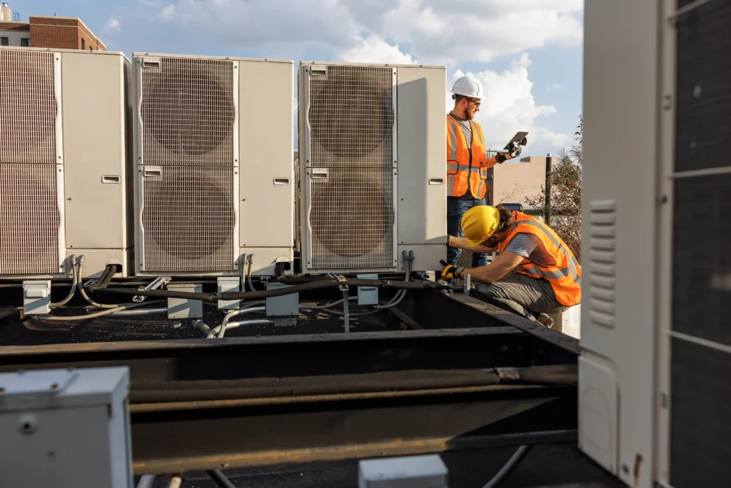 Commercial HVAC Services 1 Two men repairing a large air conditioning unit outdoors.