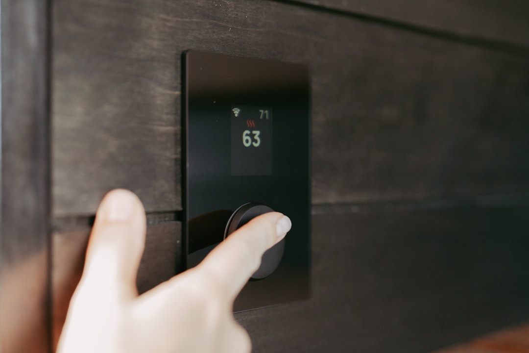 homeowner inspecting digital thermostat on interior wall