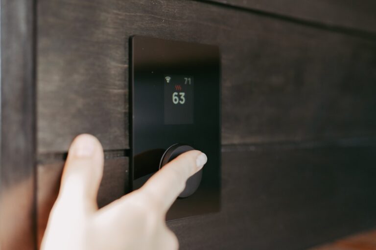 homeowner inspecting digital thermostat on interior wall